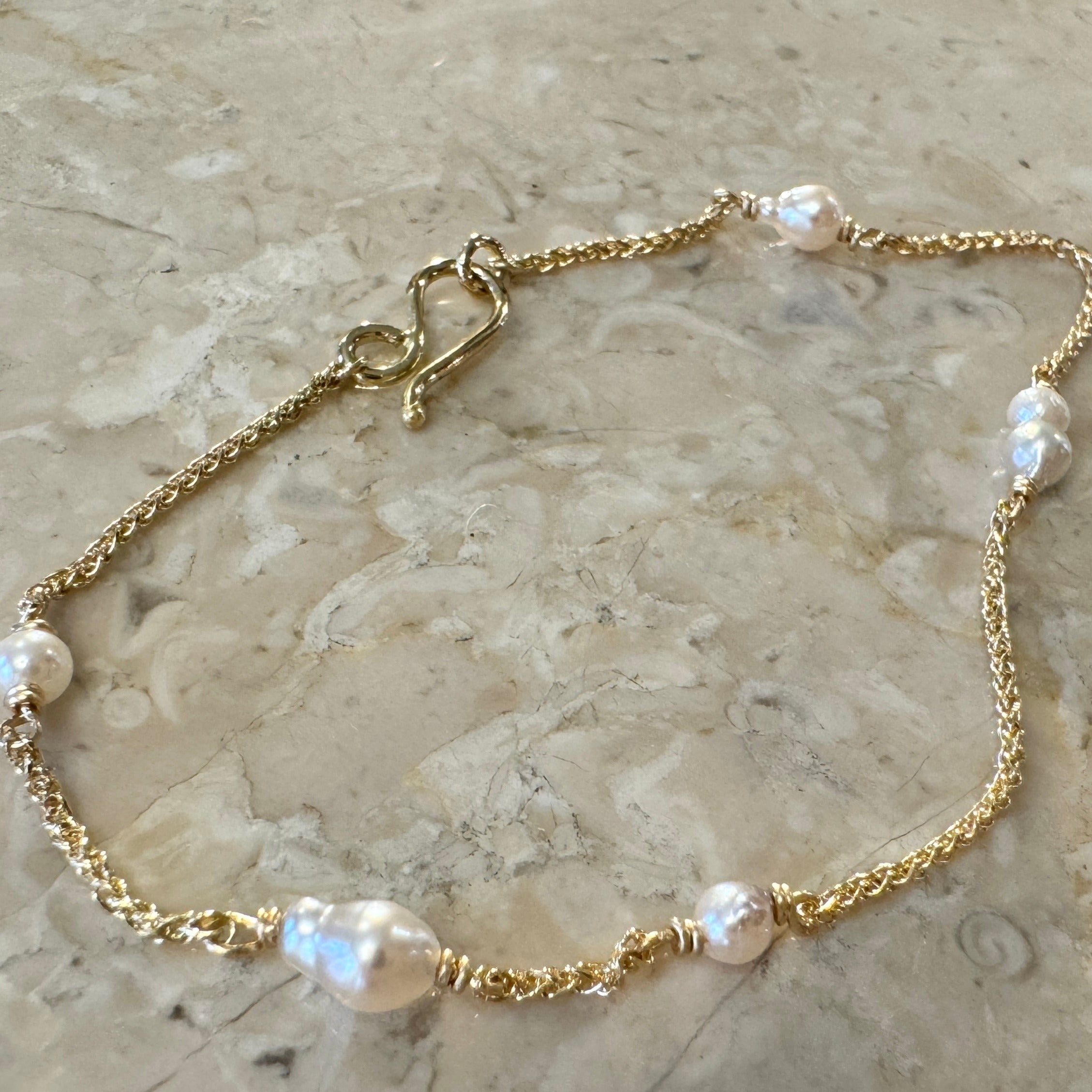 Armbånd i 18 karat guld med små lyse Akoya perler