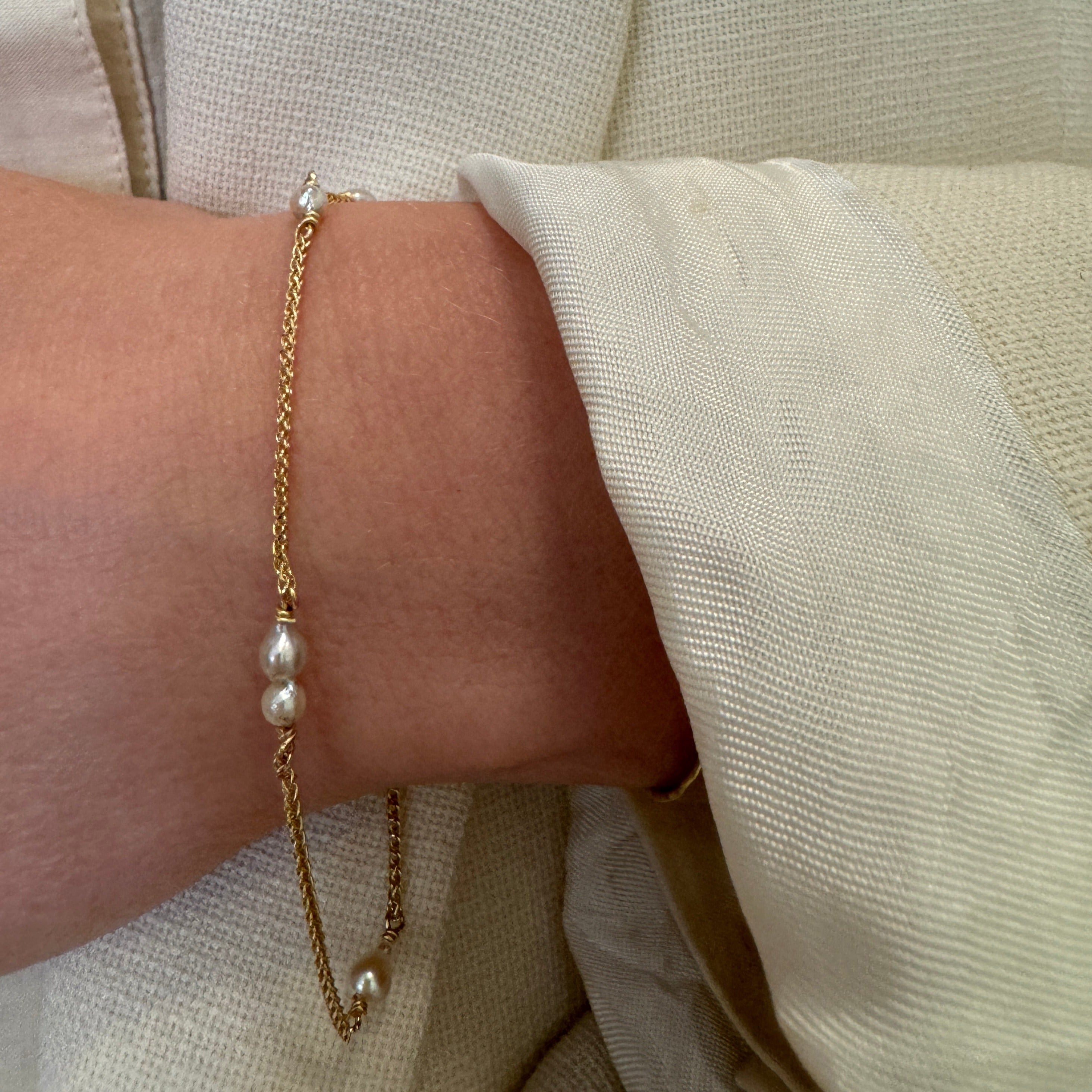 Armbånd i 18 karat guld med små lyse Akoya perler