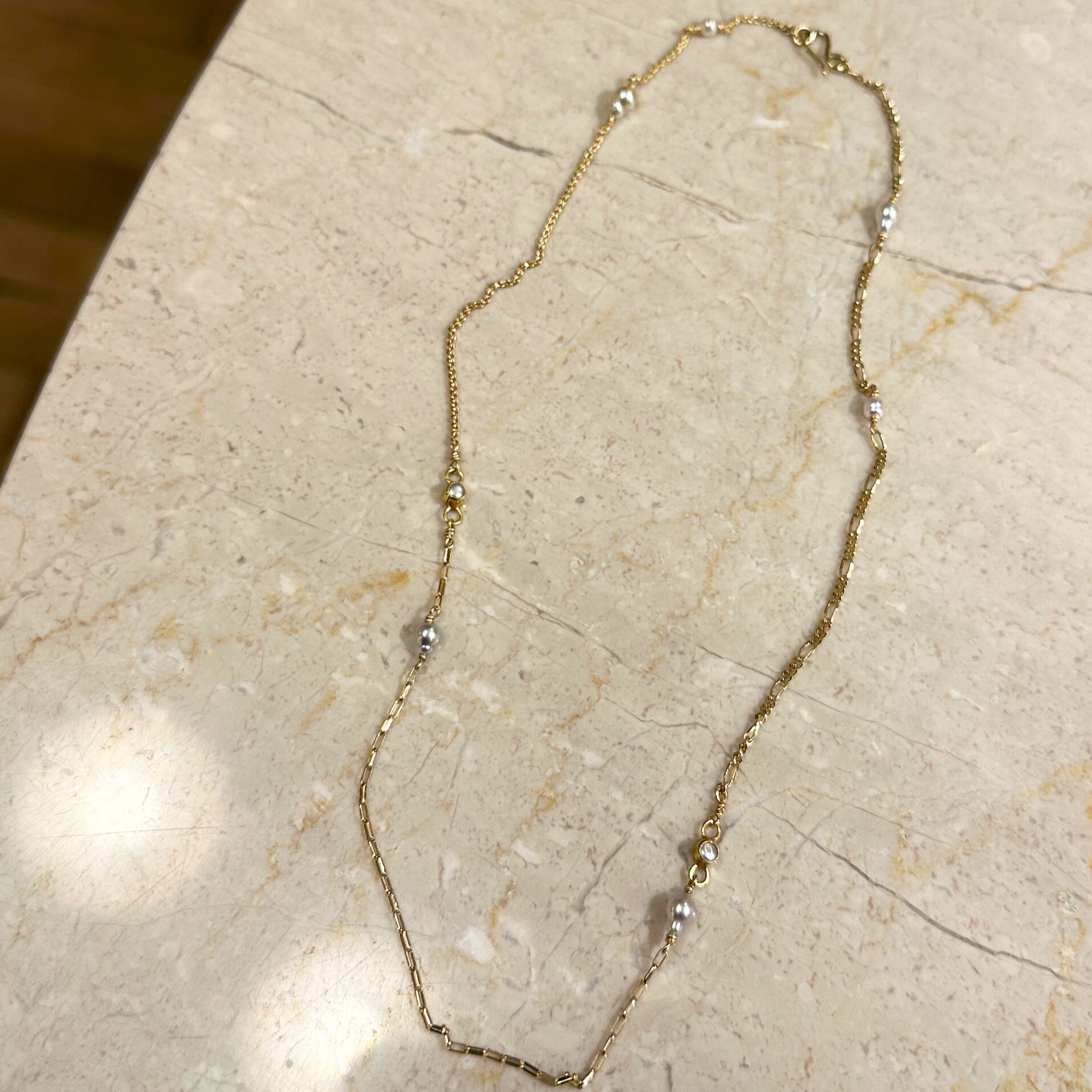 Halskæde med forskellige guldkæder og små lyse Akoya perler