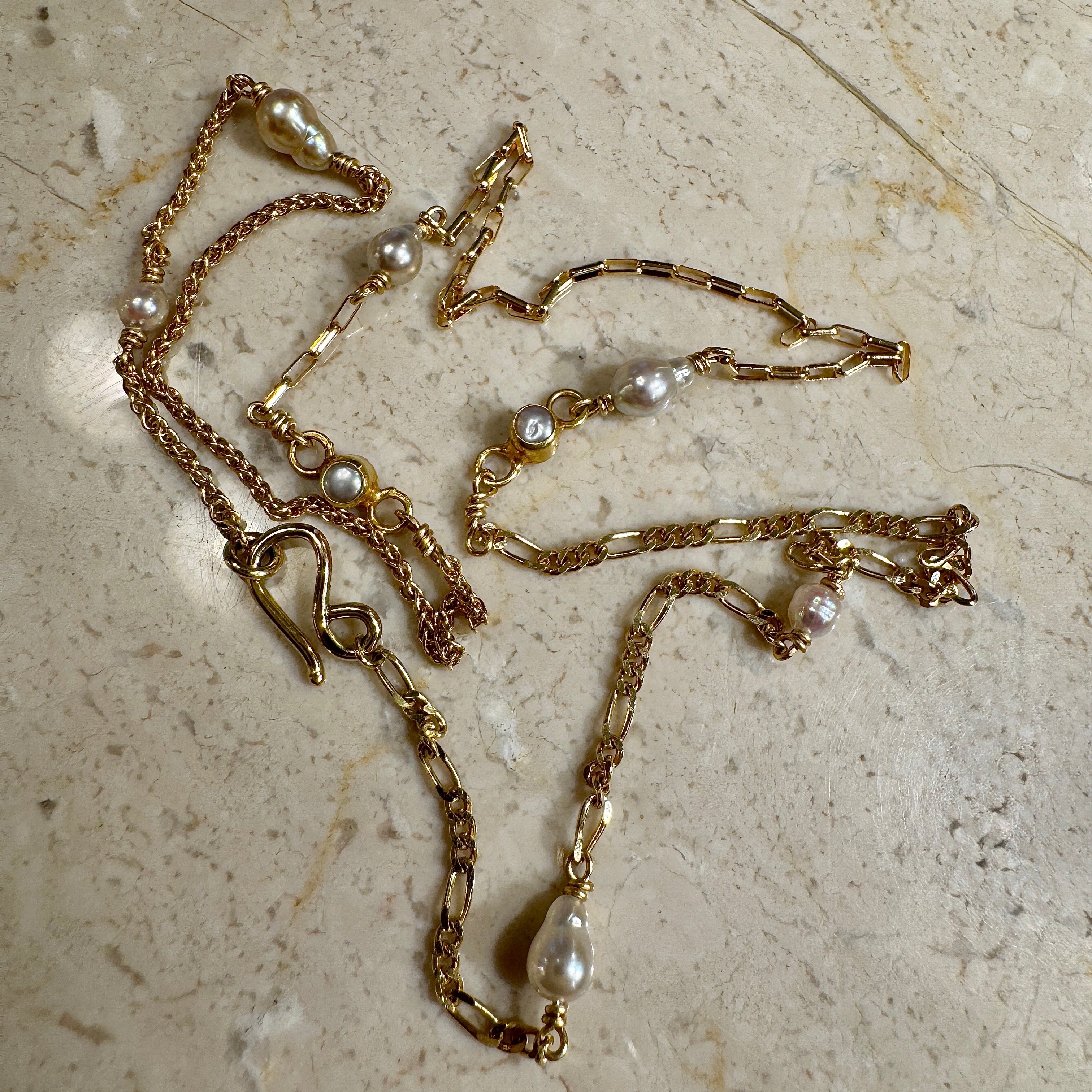 Halskæde med forskellige guldkæder og små lyse Akoya perler