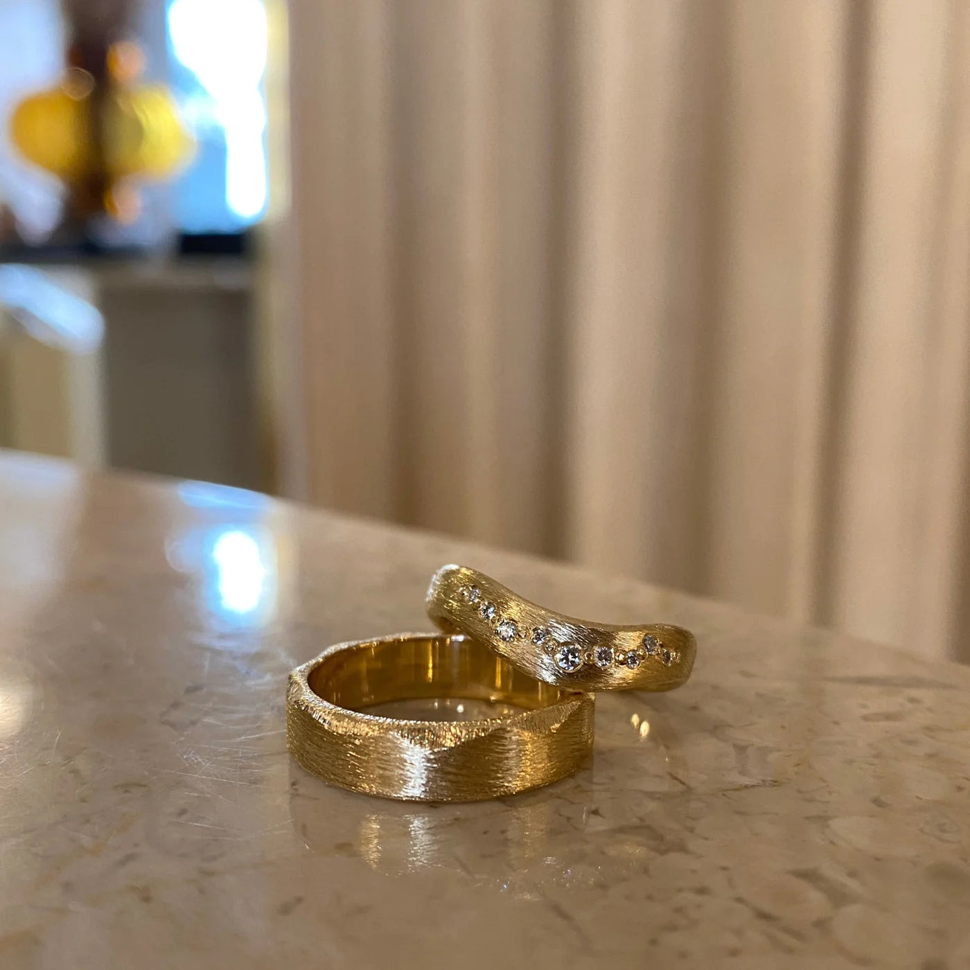 Bølgering i 18 karat guld med ridset overflade og små hvide diamanter. Herrering i 18 karat med ridset overflade og filede facetter